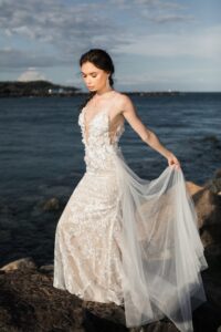 woman-wearing-white-floral-wedding-dress-standing-on-rocks-2122363